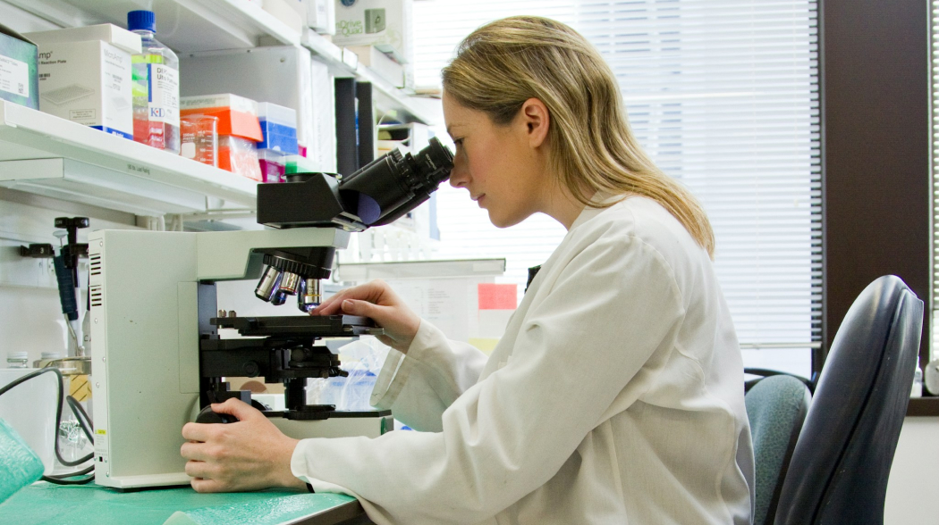 científica mirando por un microscopio